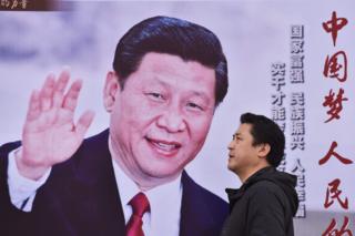A man walks past a poster featuring Chinese President Xi Jinping with a slogan reading "Chinese Dream, People"s Dream" beside a road in Beijing on 16 October 2017