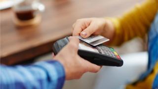 Покупатель оплачивает кофе с помощью бесконтактной платежной карты
