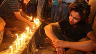 Jóvenes lloran frente a unas velas