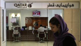 An Iranian woman walks past a Qatar Airways office in Tehran on 6 June 2017