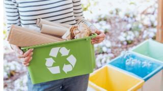 Изображение молодой женщины, сортирующей бумажные отходы для переработки