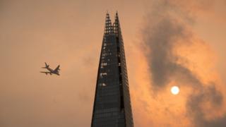 A plane flying past the Shard in London