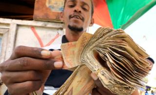 A dealer counts bundles of cash at an open air currency exchange bureau within the Hamarweyne open air market in Mogadishu, Somalia, 5 February 2020