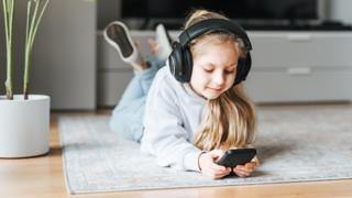 Child using a phone with headphones