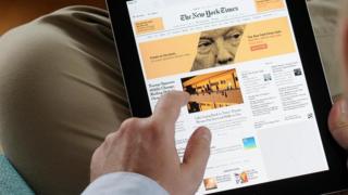 Homem vê página do The New York Times em tela de tablet