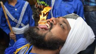 Un nihang, de la orden de guerreros armados sij, sostiene un cubo inflamable en su lengua en Amritsar, en India.