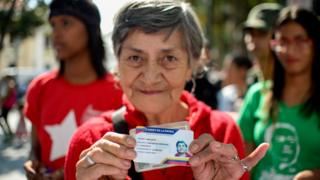 Una señora sujeta su carnet de la patria.