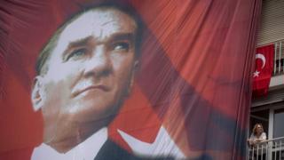 A woman watches from her balcony next to a huge banner of Mustafa Kemal Ataturk in this 2016 photo.