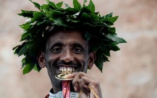 Ethiopia's Tebalu Zawude Heyi bites the winner's medal as he celebrates on the podium after winning the 25th edition of the men's Rome Marathon in Rome, Italy - Sunday 7 April 2019