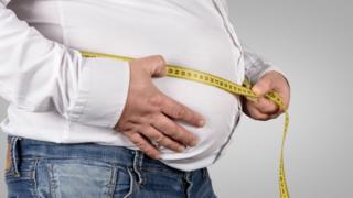 Obese man measuring belly