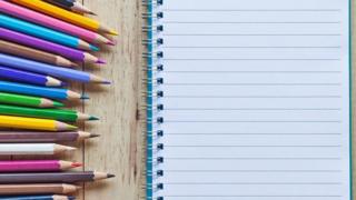 Un cuaderno con una hoja en blanco y creyones