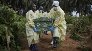 Ebola workers carrying a coffin