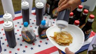 A man pouring maple syrup onto pancakes at the Polk County Steak Fry