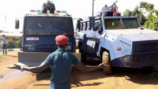 Uganda music star Bobi Wine dey stand in front of two armoured vehicle