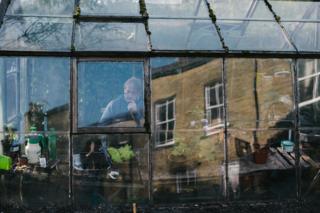 A man works in a greenhouse in his garden