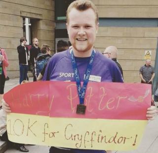 Harry Potter holding a banner which reads 'Harry Potter 10k for Gryffindor' at a Manchester 10k