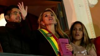 Jeanine Anez holding a bible as she addresses supporters from a balcony.