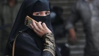 A Muslim woman talks on her phone as she walks in the old Delhi city area, India, 22 August 2017