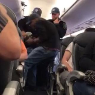 The man who is believed to be a doctor is dragged out of his seat by flight security