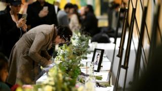 A woman writes in a memorial book at a service for victims of the plane crash in Edmonton, Canada