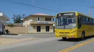 Ônibus passa em frente a casa com placa que diz: "Pescaria Brava"
