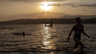 Menschen genießen das Baden bei Sonnenaufgang im Genfer See in Genf, Schweiz