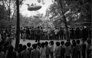 A crowd watches a ride at a fairground