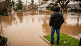 A man looks at the flooded intersection in Santa Barbara, California