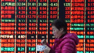 A woman walks past stock market board in China