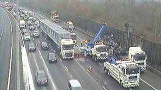 The carcass of the coach being lifted onto a flatbed lorry for removal