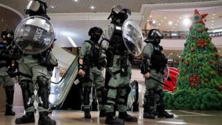 Полиция со щитами в шлемах возле украшенной елки