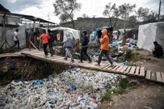 in_pictures Children walk over a bridge in the Moria migrant camp