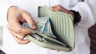 A woman opening her purse and looking at money