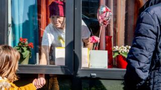 Reijnen family in Tilburg, Netherlands, saying goodbye to grandmother Van Baast behind a window of a care home as the only protective measure against the spread of coronavirus. 28 March 2020