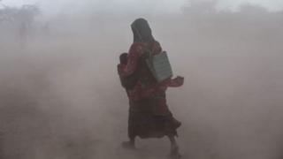 አንድት ሴት ህፃን ይዛ እየተራመደች
