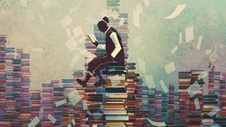 Alguien leyendo sobre pilas de libros