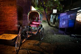 A bicycle rickshaw in a dimly lit back street in Bangladesh. F M Hall Rickshaw. Part of 'Crossfire', a photo story by Shahidul Alam.