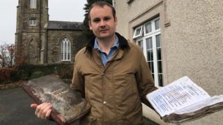 Rev Alastair Donaldson holding the church register books