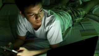 Child on phone in bed at night
