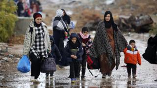People walking outside with jackets and jumpers as they travel south in Gaza, on 27 November