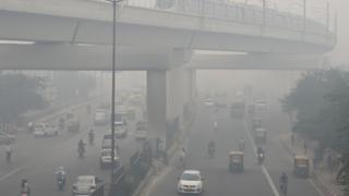 A Delhi Metro train (top) and vehicles drive past amid heavy smog in New Delhi on November 5, 2018
