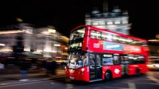Bus tingkat di London melaju di malam hari.
