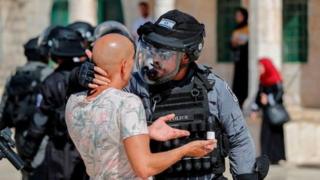 رجل شرطة إسرائيلية ممسكا بشاب فلسطيني