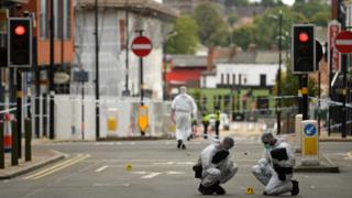 Police forensic officers gather evidence inside a cordon on Hurst Street