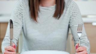 A woman sits at a table on an empty plate