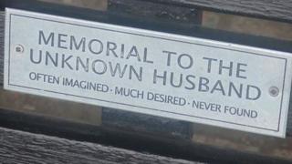 Bench dedication: "Memorial to the unknown husband. Often imagined. Much desired. Never found."