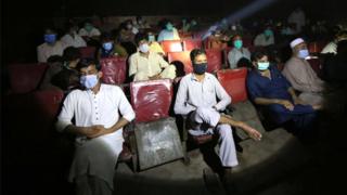 People wearing face masks watch a movie in the cinema after the government lifted most of the country's remaining coronavirus restrictions, in Peshawar, Pakistan, 10 August 2020.