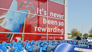 An exterior display of a Tesco shows a huge advert for Tesco Clubcard dominating the building