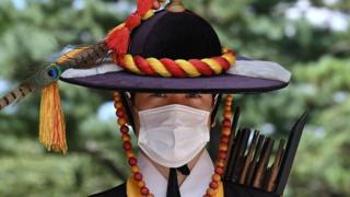 A palace guard member wearing a face mask stands for tourists at the main gate of Deoksugung Palace in Seoul on September 4, 2020.