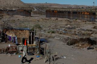 A child plays with a ball at his house as a newly built section of the US-Mexico border fence is seen in the background at Anapra neighbourhood in Ciudad Juarez, Mexico